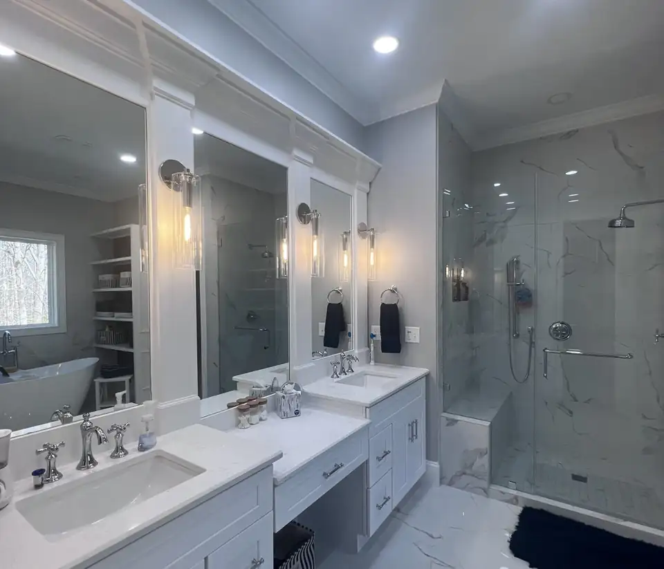 Bathroom remodeling Cary NC: white double vanity with makeup counter, marble-pattern porcelain and a frameless glass shower in a Cary home