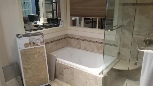 Raleigh bathroom with built-in soaking tub, beige stone tile surround and frameless glass shower