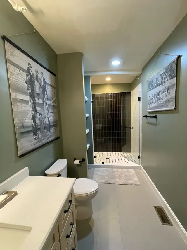 Bathroom remodel with navy walls, gray vanity, white top and tiled walk-in shower with niche