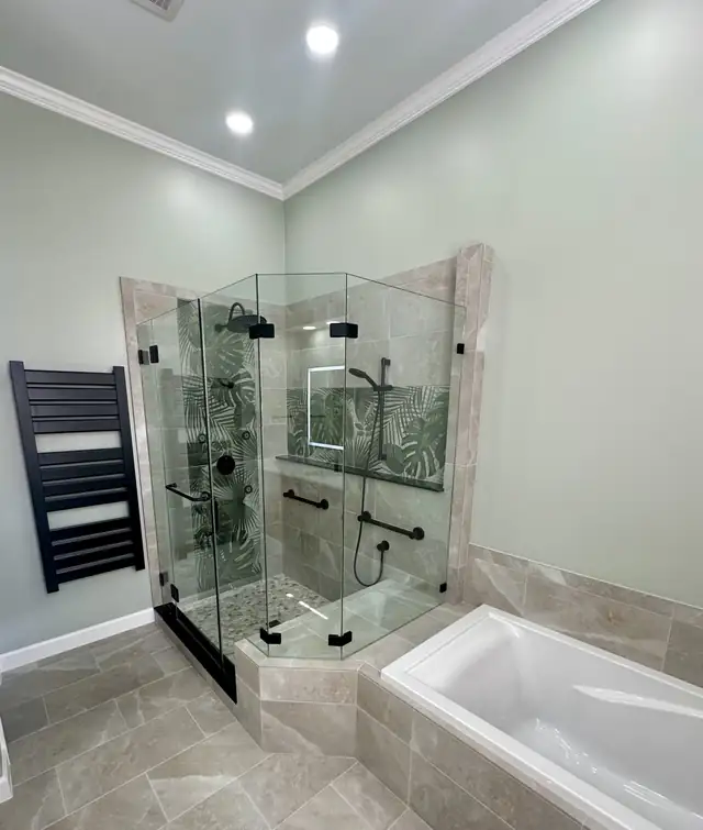 Primary bathroom with black accent walls, white vanity, marble-look floor and frameless glass shower